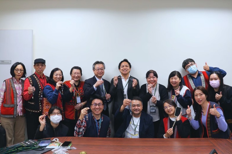 日本沖繩石垣島博物館觀摩來賓，手持各自南島風手機鍊成果，與工作人員合影。（圖／黃歆𡩋）
