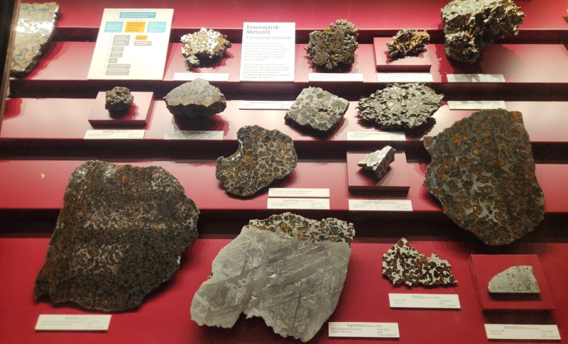 展櫃第一列中可見到人類科學史上認定的第一塊石鐵隕石 – Krasnojarsk 橄欖隕鐵。橄欖隕鐵切面呈現金黃色的橄欖石晶體，與銀色的鐵鎳合金交相輝映，是被公認為最美麗的隕石類型。（圖／陳君榮）
