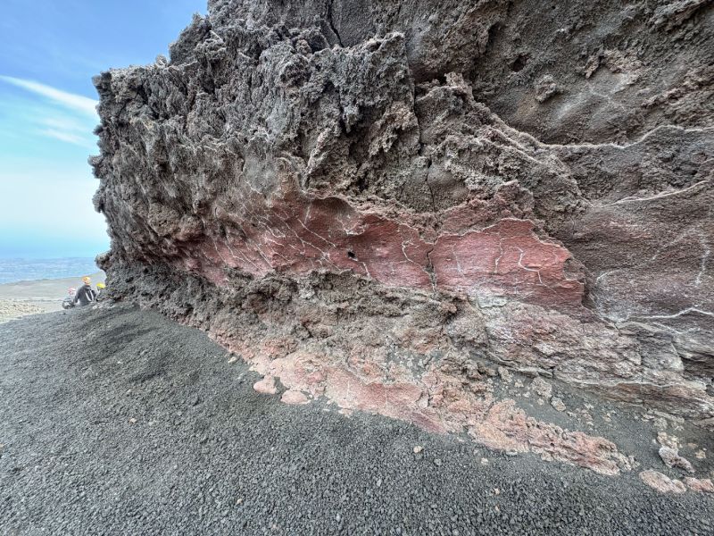 埃特納火山步道旁可見的冷卻岩漿通道(Lava Tube)。熔岩流動時,表層迅速冷卻形成堅硬外殼,內部熔岩仍持續流動,待熔岩排空後,留下中空的岩漿通道。(圖/何恭睿)